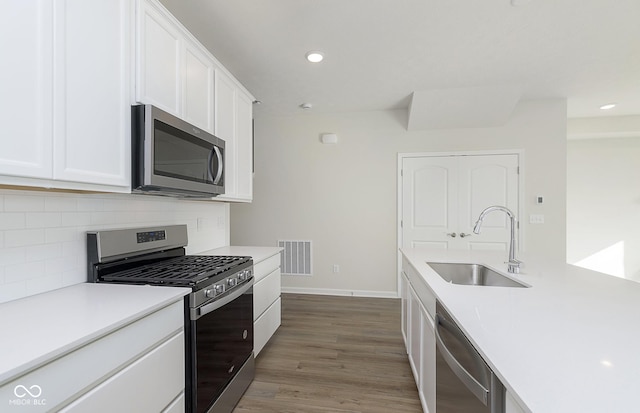 9741 Oleander Dr, Fishers, IN 46250 - kitchen featuring appliances with stainless steel finishes, a sink, white cabinetry, tasteful backsplash, and baseboards