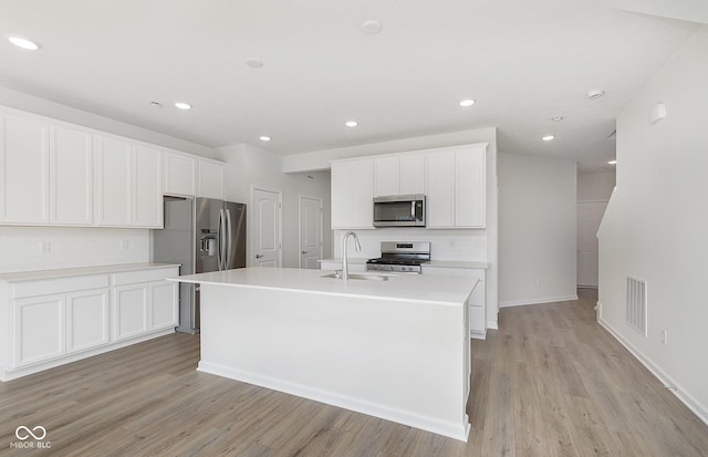9741 Oleander Dr, Fishers, IN 46250 - kitchen featuring appliances with stainless steel finishes, a sink, backsplash, light wood finished floors, and an island with sink