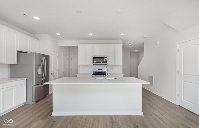 9741 Oleander Dr, Fishers, IN 46250 - kitchen with appliances with stainless steel finishes, a center island with sink, backsplash, a sink, and light wood finished floors