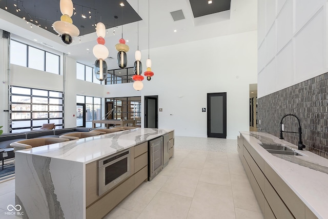 9741 Oleander Dr, Fishers, IN 46250 - kitchen featuring a high ceiling, a sink, modern cabinets, stainless steel microwave, and light tile patterned floors