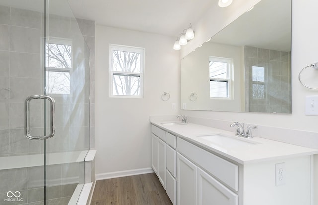 9741 Oleander Dr, Fishers, IN 46250 - bathroom with double vanity, wood finished floors, a tile shower, and baseboards