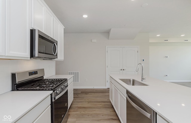 9741 Oleander Dr, Fishers, IN 46250 - kitchen featuring appliances with stainless steel finishes, white cabinets, light countertops, light wood finished floors, and tasteful backsplash