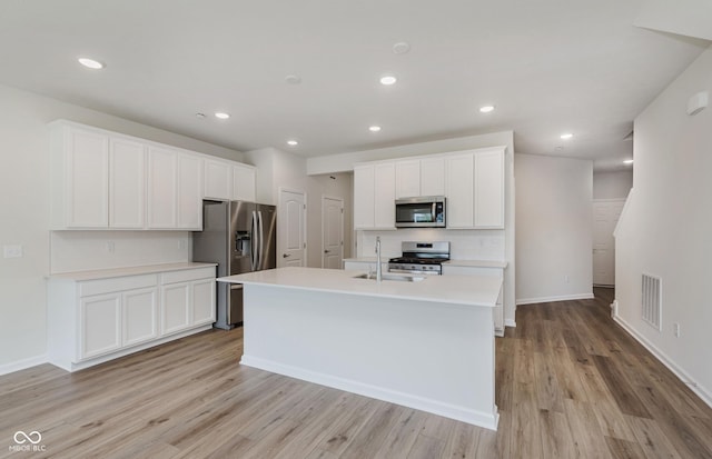 9741 Oleander Dr, Fishers, IN 46250 - kitchen featuring appliances with stainless steel finishes, light wood-type flooring, light countertops, a kitchen island with sink, and white cabinetry
