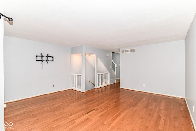 558 E Vermont St, Indianapolis, IN 46202 - empty room featuring light wood-style floors, baseboards, and stairway