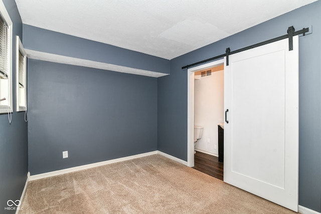 558 E Vermont St, Indianapolis, IN 46202 - unfurnished bedroom with a barn door, carpet floors, and baseboards
