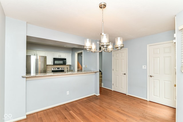 558 E Vermont St, Indianapolis, IN 46202 - kitchen with stainless steel appliances, a chandelier, light wood-style flooring, baseboards, and white cabinetry