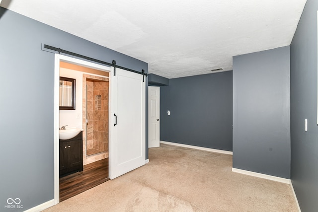 558 E Vermont St, Indianapolis, IN 46202 - unfurnished bedroom with carpet flooring, baseboards, a sink, and a barn door