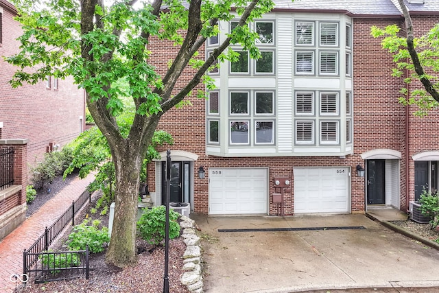 558 E Vermont St, Indianapolis, IN 46202 - view of front of home featuring concrete driveway, a garage, central air condition unit, and brick siding