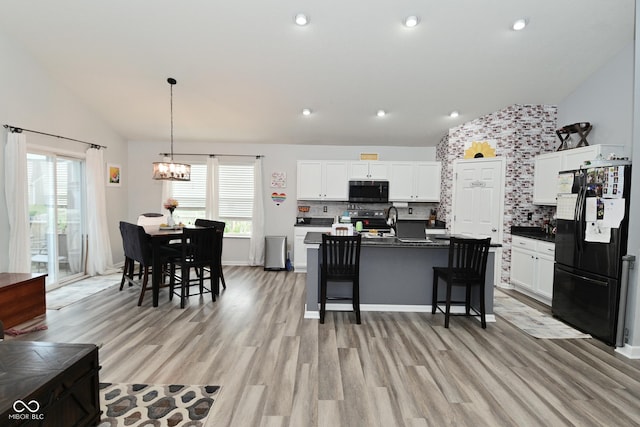 7515 Brattle Dr, Indianapolis, IN 46113 - kitchen featuring appliances with stainless steel finishes, lofted ceiling, a chandelier, a breakfast bar, and dark countertops