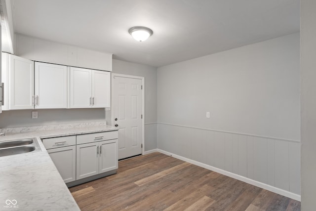 1002 Collier St, Indianapolis, IN 46241 - kitchen featuring light wood-style flooring, light countertops, white cabinets, a wainscoted wall, and a sink