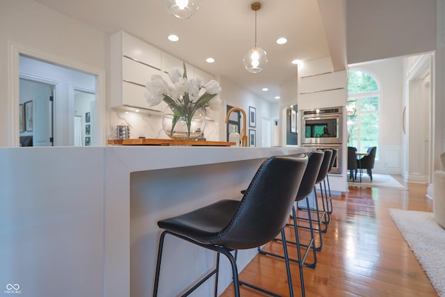 11911 W Grandview Dr, Columbus, IN 47201 - kitchen featuring modern cabinets, white cabinetry, a breakfast bar, decorative light fixtures, and light wood finished floors