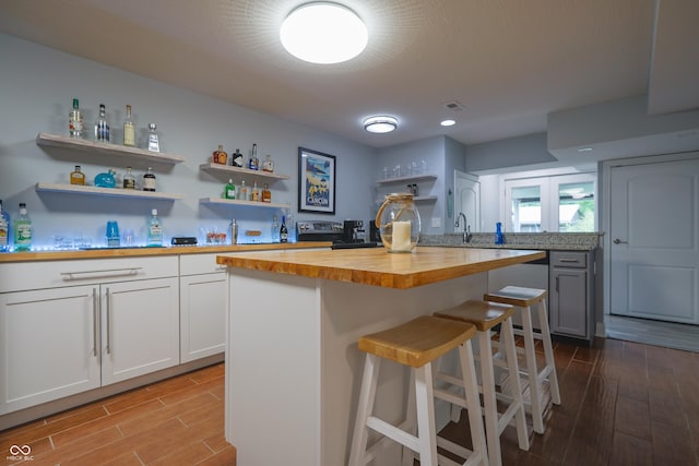 11911 W Grandview Dr, Columbus, IN 47201 - kitchen with wood counters, wood finished floors, a breakfast bar area, open shelves, and white cabinetry