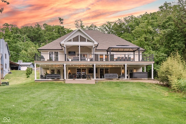 11911 W Grandview Dr, Columbus, IN 47201 - back of house at dusk featuring a balcony, a yard, ceiling fan, and a hot tub