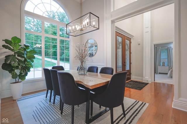 11911 W Grandview Dr, Columbus, IN 47201 - dining space with french doors, a chandelier, wood finished floors, a decorative wall, and a towering ceiling