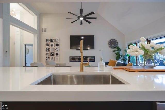 11911 W Grandview Dr, Columbus, IN 47201 - kitchen featuring a glass covered fireplace, open floor plan, ceiling fan, light countertops, and high vaulted ceiling