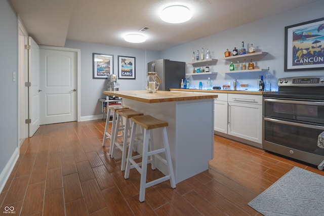 11911 W Grandview Dr, Columbus, IN 47201 - kitchen featuring stainless steel appliances, wood counters, dark wood-style flooring, white cabinetry, and a breakfast bar