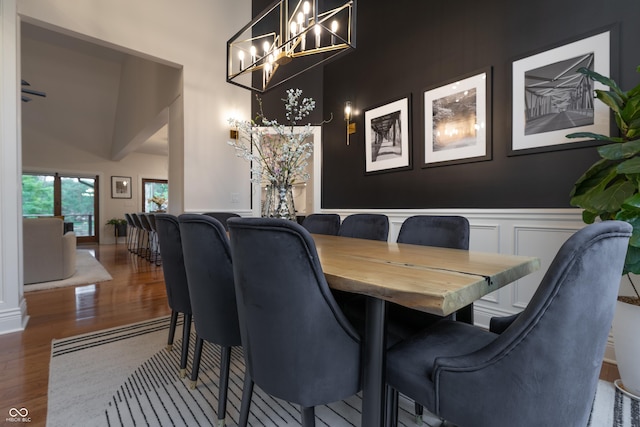 11911 W Grandview Dr, Columbus, IN 47201 - dining space featuring a chandelier, wood finished floors, a high ceiling, a decorative wall, and a wainscoted wall
