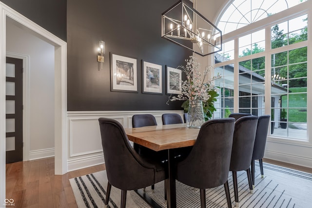 11911 W Grandview Dr, Columbus, IN 47201 - dining area with a chandelier, wood finished floors, a decorative wall, a wainscoted wall, and baseboards