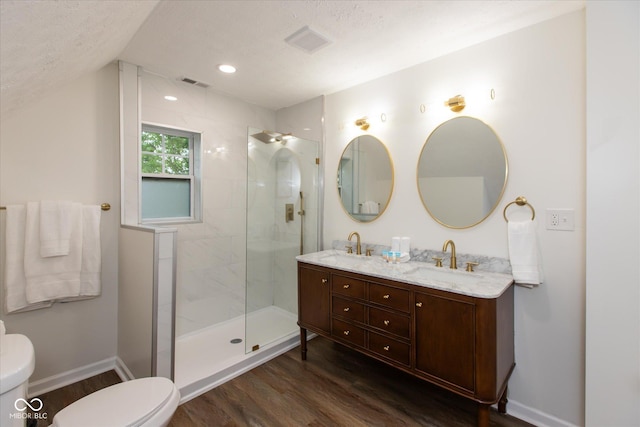 2623 Guilford Ave, Indianapolis, IN 46205 - bathroom with toilet, wood finished floors, a tile shower, double vanity, and vaulted ceiling