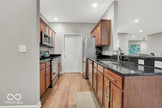 435 Virginia Ave Unit 108, Indianapolis, IN 46203 - kitchen with stainless steel appliances, brown cabinets, light wood-style floors, dark stone countertops, and a sink