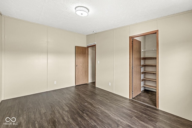 5428 S 525 W, Williamsport, IN 47993 - unfurnished bedroom featuring wood finished floors, a spacious closet, a closet, a textured ceiling, and a decorative wall