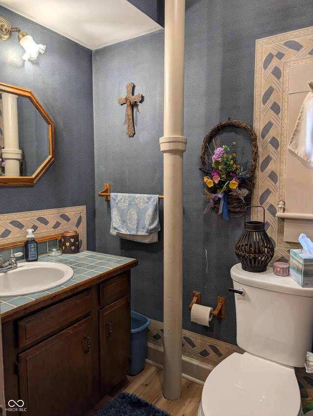 150 W Walnut St, North Vernon, IN 47265 - bathroom with wood finished floors, toilet, ornate columns, and vanity