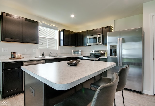 9829 Hulton Rd, Pendleton, IN 46064 - kitchen with appliances with stainless steel finishes, a sink, a breakfast bar, light wood-style flooring, and a center island