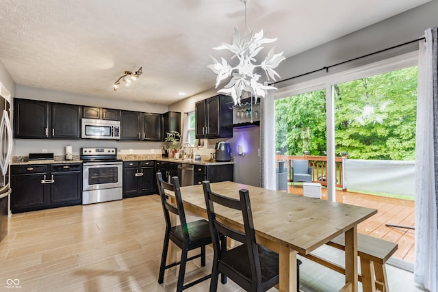11919 Gatwick View Dr, Fishers, IN 46037 - kitchen with stainless steel appliances, a chandelier, light wood-style flooring, light stone countertops, and a sink