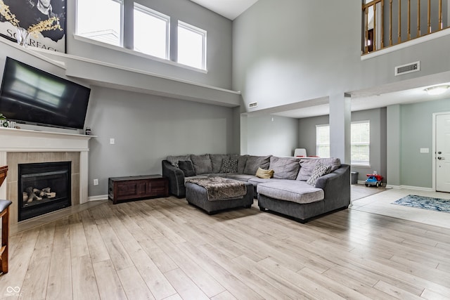 11919 Gatwick View Dr, Fishers, IN 46037 - living room featuring a high ceiling, wood finished floors, healthy amount of natural light, a tile fireplace, and baseboards