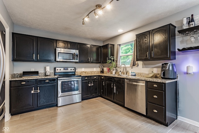11919 Gatwick View Dr, Fishers, IN 46037 - kitchen with appliances with stainless steel finishes, a sink, light stone counters, light wood-style flooring, and a textured ceiling