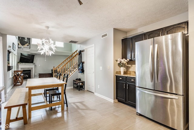 11919 Gatwick View Dr, Fishers, IN 46037 - kitchen with freestanding refrigerator, a chandelier, a textured ceiling, a fireplace, and baseboards