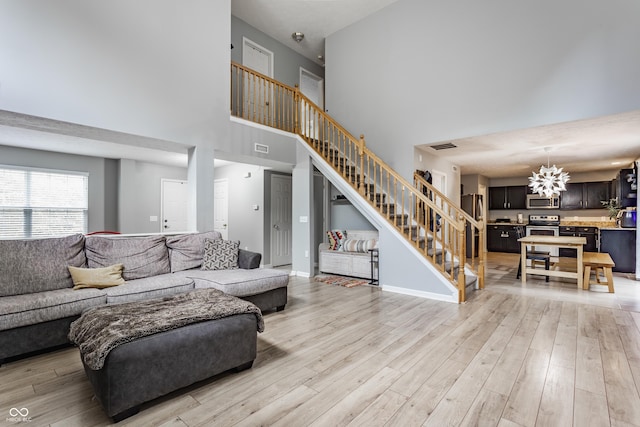 11919 Gatwick View Dr, Fishers, IN 46037 - living room featuring stairway, a towering ceiling, light wood-type flooring, and a chandelier
