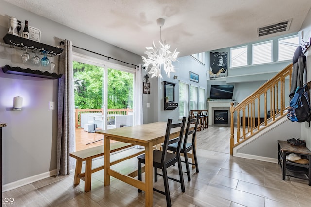 11919 Gatwick View Dr, Fishers, IN 46037 - dining room featuring stairway, a chandelier, a glass covered fireplace, a textured ceiling, and baseboards