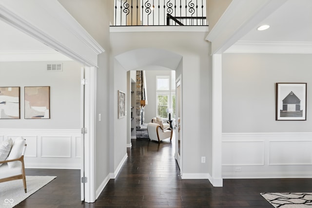 2485 Alexandra Dr, Carmel, IN 46074 - foyer featuring arched walkways, crown molding, dark wood finished floors, a decorative wall, and a wainscoted wall