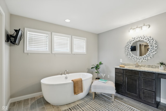 2485 Alexandra Dr, Carmel, IN 46074 - full bath featuring vanity, baseboards, a freestanding bath, wood finish floors, and recessed lighting