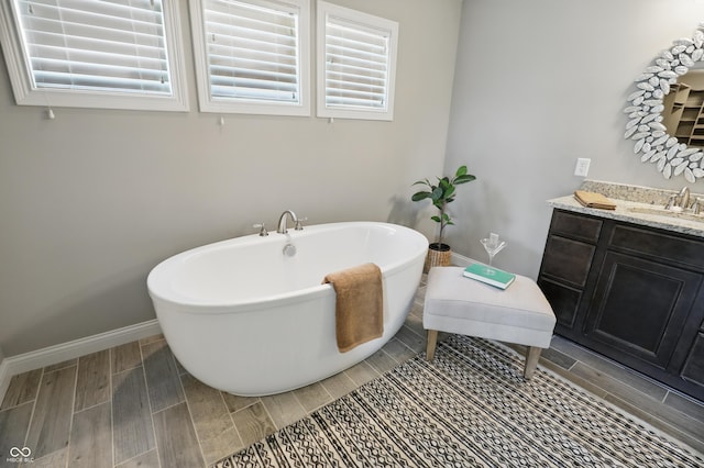 2485 Alexandra Dr, Carmel, IN 46074 - full bath with wood finish floors, a freestanding bath, vanity, baseboards, and healthy amount of natural light