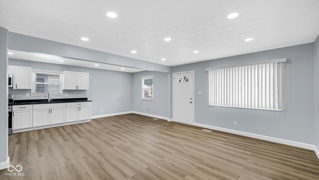 3106 N Harding St, Indianapolis, IN 46208 - unfurnished living room featuring a sink, baseboards, light wood-style floors, and recessed lighting