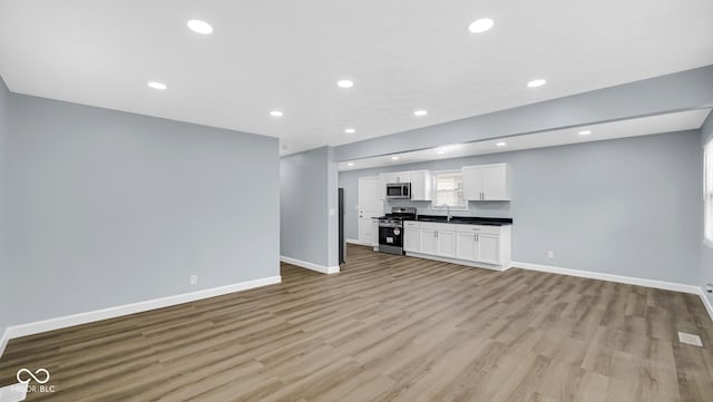 3106 N Harding St, Indianapolis, IN 46208 - unfurnished living room featuring baseboards, light wood finished floors, recessed lighting, and a sink