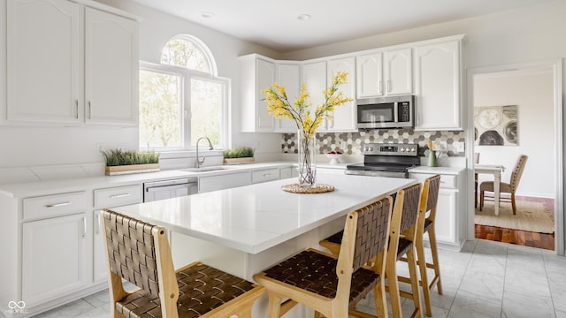734 Richland Way, Westfield, IN 46074 - kitchen featuring appliances with stainless steel finishes, light marble finish flooring, a kitchen bar, a sink, and white cabinetry