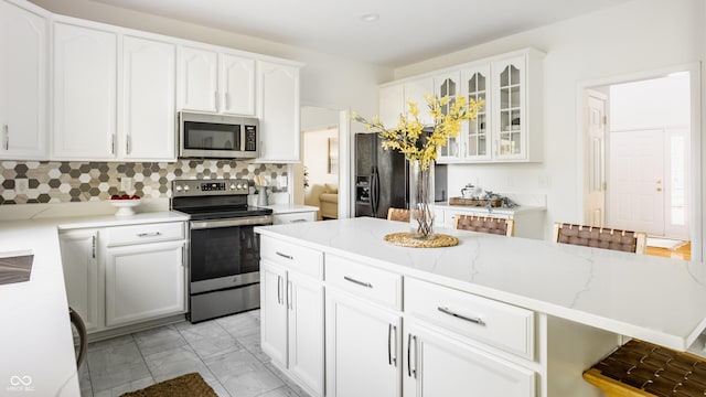 734 Richland Way, Westfield, IN 46074 - kitchen featuring stainless steel appliances, glass insert cabinets, light marble finish flooring, light stone counters, and tasteful backsplash