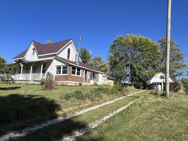 5855 S County Road 800 E, Coatesville, IN 46121 - view of side of home featuring a porch, metal roof, a lawn, and brick siding