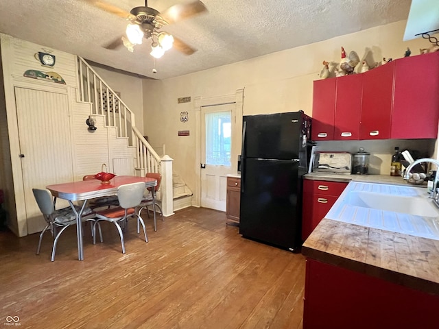 5855 S County Road 800 E, Coatesville, IN 46121 - kitchen with freestanding refrigerator, a textured ceiling, hardwood / wood-style flooring, red cabinetry, and ceiling fan