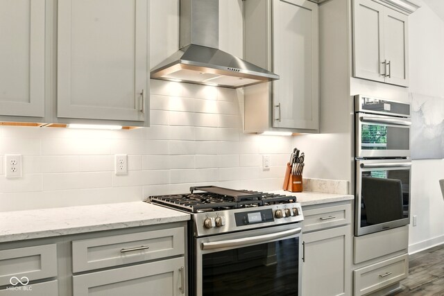19257 Red Willow Ln, Noblesville, IN 46062 - kitchen with appliances with stainless steel finishes, wall chimney exhaust hood, decorative backsplash, dark wood-style floors, and light stone counters