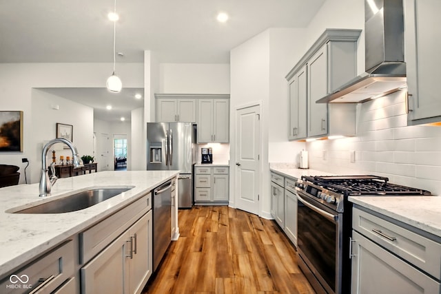 19257 Red Willow Ln, Noblesville, IN 46062 - kitchen featuring wall chimney exhaust hood, appliances with stainless steel finishes, a sink, gray cabinets, and light wood-style flooring
