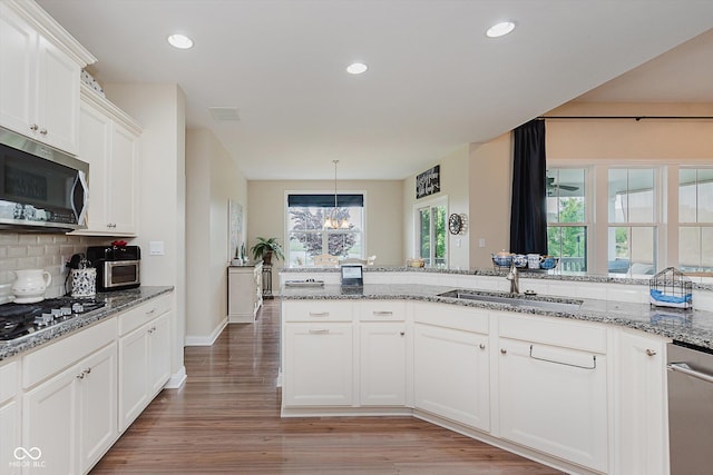 6337 Ederline Ln, Noblesville, IN 46062 - kitchen with stainless steel appliances, a sink, decorative backsplash, white cabinets, and light stone countertops