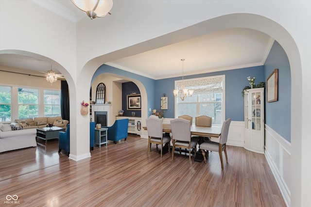 6337 Ederline Ln, Noblesville, IN 46062 - dining area featuring a chandelier, a fireplace, light wood finished floors, crown molding, and wainscoting