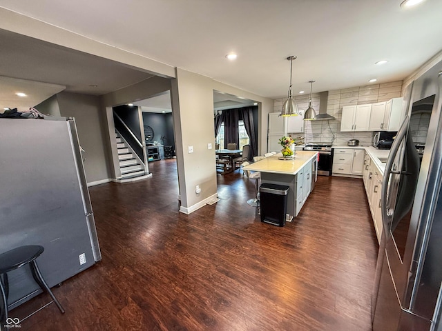 201 N Tacoma Ave, Indianapolis, IN 46201 - kitchen with stainless steel appliances, wall chimney range hood, light countertops, dark wood-style flooring, and white cabinets