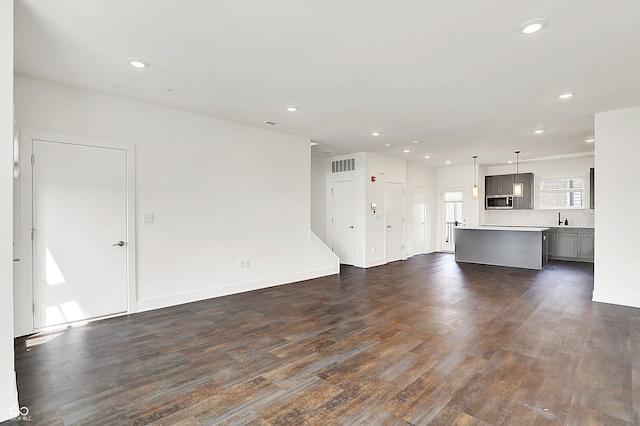 727 N Illinois St Unit 202, Indianapolis, IN 46204 - unfurnished living room featuring dark wood-style flooring, recessed lighting, a sink, and baseboards