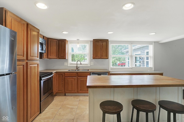6838 Five Points Rd, Indianapolis, IN 46259 - kitchen with appliances with stainless steel finishes, wooden counters, a sink, a kitchen bar, and brown cabinets