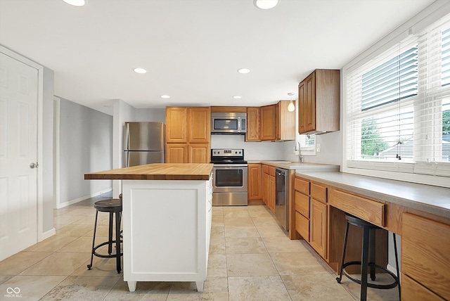 6838 Five Points Rd, Indianapolis, IN 46259 - kitchen featuring appliances with stainless steel finishes, a breakfast bar, a sink, light tile patterned floors, and recessed lighting